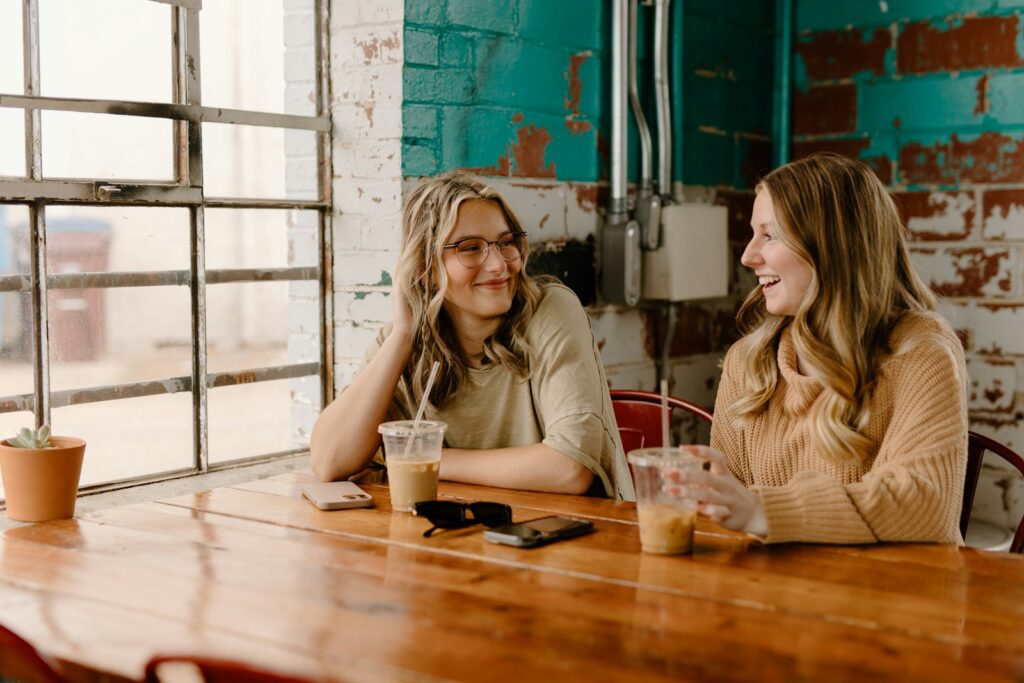 Two women talking across a wooden table