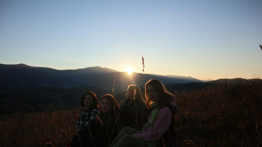 Friends standing together on a hill at sunset